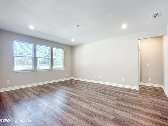 unfurnished room with recessed lighting, visible vents, wood finished floors, and baseboards