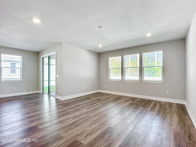 unfurnished living room featuring recessed lighting, a textured ceiling, baseboards, and dark wood-type flooring