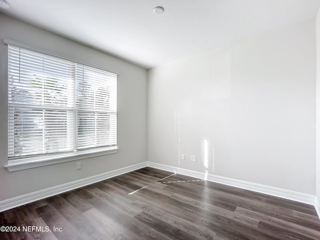 spare room with wood finished floors, a healthy amount of sunlight, and baseboards