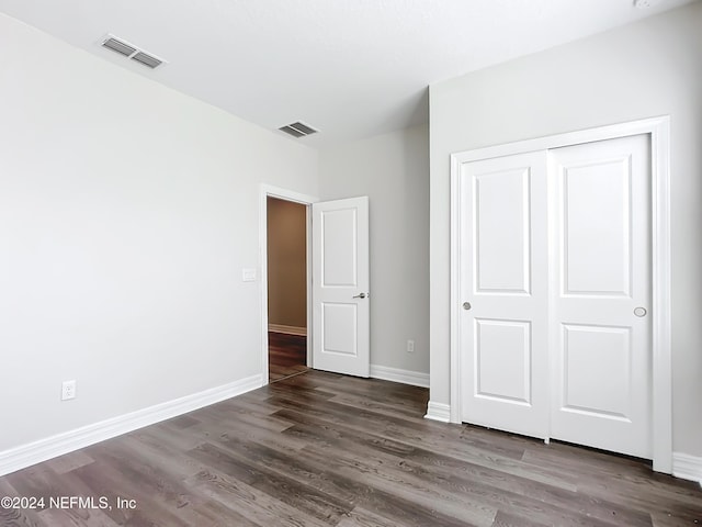 unfurnished bedroom featuring baseboards, visible vents, wood finished floors, and a closet