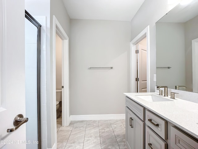full bath featuring vanity, toilet, a shower with shower door, marble finish floor, and baseboards