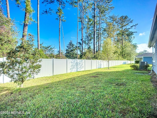 view of yard featuring fence and central AC unit