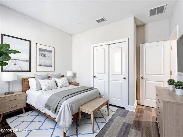bedroom with a closet, visible vents, and dark wood finished floors