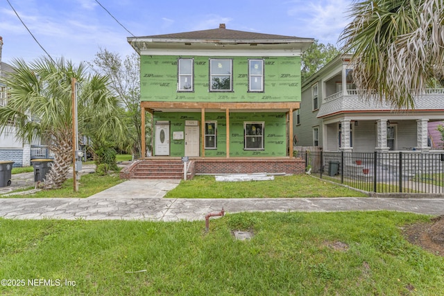 view of front facade featuring covered porch, fence, and a front lawn