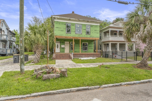 view of front of home featuring fence, a porch, a front yard, a chimney, and a balcony