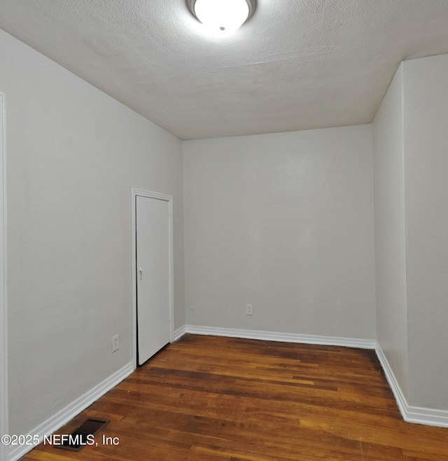 unfurnished room featuring dark wood finished floors, baseboards, and a textured ceiling