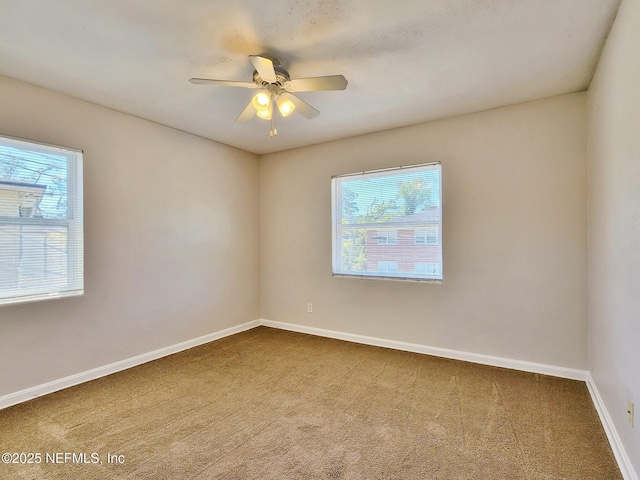 spare room featuring a wealth of natural light, a ceiling fan, carpet flooring, and baseboards