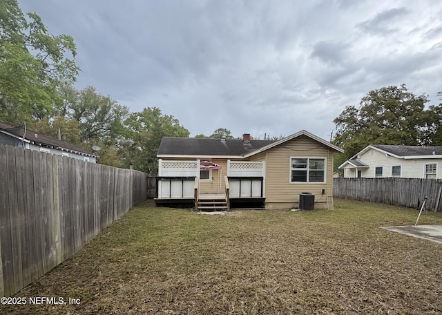 rear view of house with a deck, central AC unit, a yard, and a fenced backyard