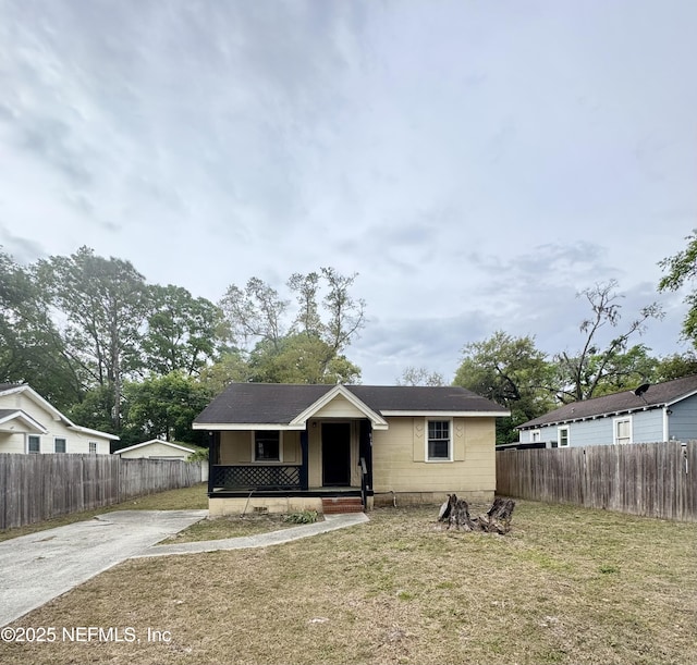 bungalow-style home with a front yard, driveway, covered porch, and fence