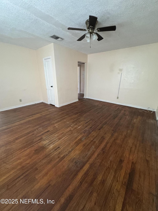 unfurnished room featuring ceiling fan, baseboards, visible vents, a textured ceiling, and dark wood-type flooring