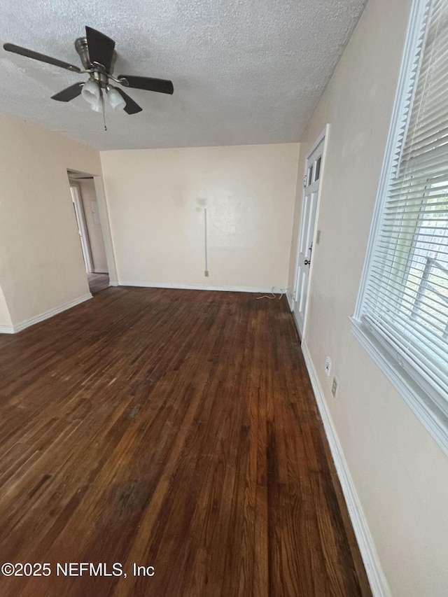 empty room with a ceiling fan, a textured ceiling, and dark wood-type flooring