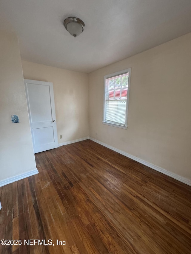 unfurnished room featuring baseboards and dark wood-style flooring