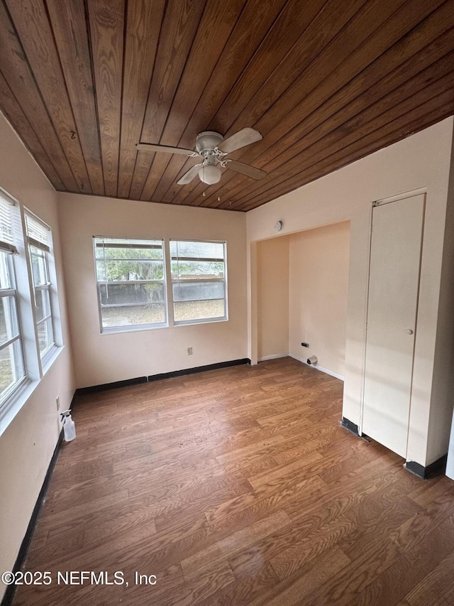 unfurnished room featuring wood finished floors, a ceiling fan, baseboards, and wooden ceiling