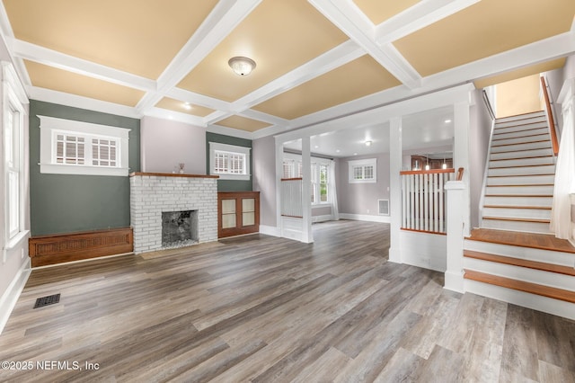 unfurnished living room with visible vents, coffered ceiling, stairs, and wood finished floors