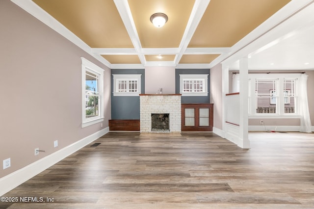 unfurnished living room with a brick fireplace, baseboards, beamed ceiling, visible vents, and coffered ceiling
