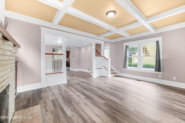 unfurnished living room with a fireplace, wood finished floors, baseboards, beamed ceiling, and coffered ceiling
