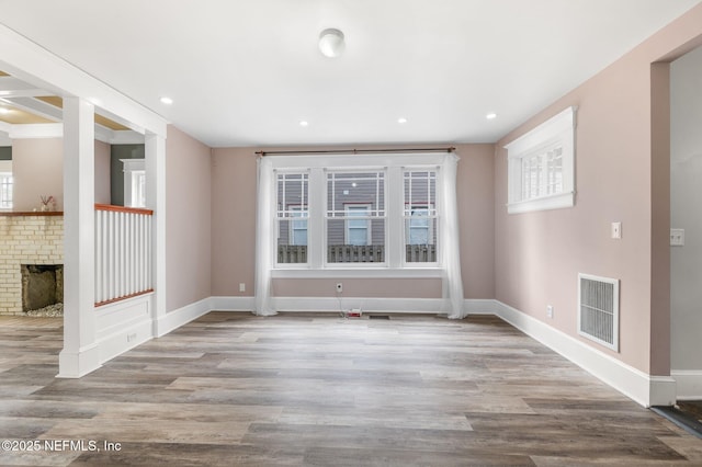 spare room with visible vents, baseboards, wood finished floors, and a fireplace