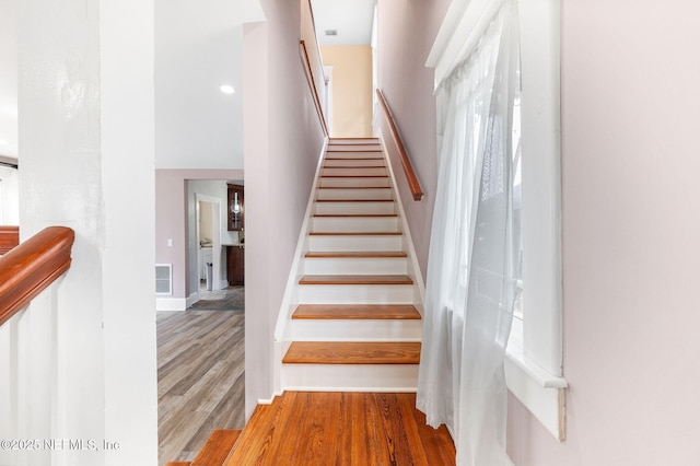 stairway with visible vents, baseboards, and wood finished floors