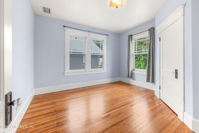 empty room with light wood-style floors, baseboards, and visible vents