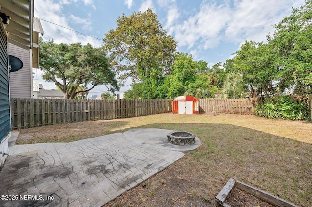 view of yard with a storage shed, an outdoor structure, a fenced backyard, a patio, and a fire pit