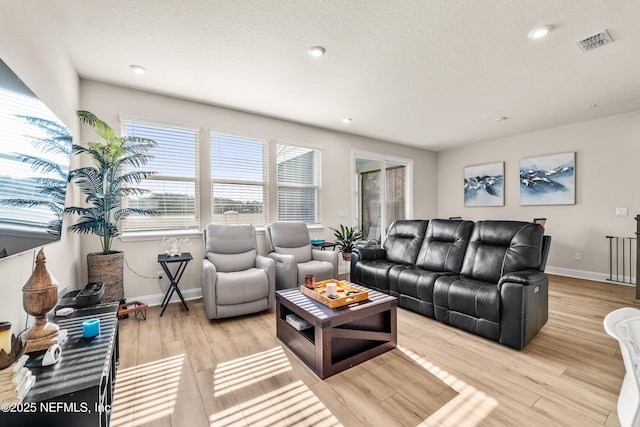 living room featuring light wood-style flooring, baseboards, recessed lighting, and a textured ceiling