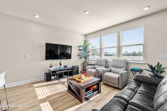 living area with light wood-style floors, baseboards, a textured ceiling, and recessed lighting