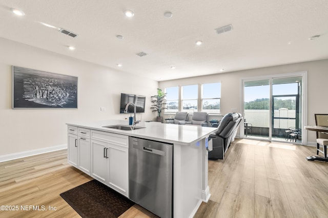 kitchen featuring stainless steel dishwasher, a sink, light wood-type flooring, light countertops, and white cabinetry