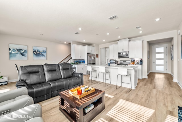 living room with light wood-style floors, recessed lighting, baseboards, and stairs