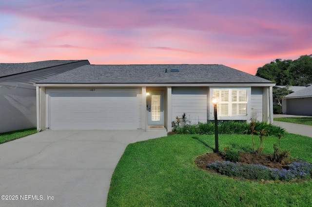 single story home featuring a yard, roof with shingles, concrete driveway, and a garage
