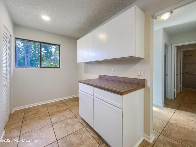 3801 Crown Point Rd Unit 1311, Jacksonville, FL 32257 - kitchen featuring light tile patterned floors, a textured ceiling, white cabinetry, and butcher block counters