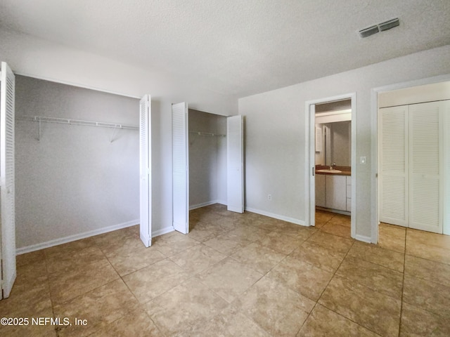 3801 Crown Point Rd Unit 1311, Jacksonville, FL 32257 - unfurnished bedroom featuring light tile patterned floors, a textured ceiling, visible vents, baseboards, and two closets