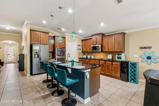 417 Palazzo Cir, Saint Augustine, FL 32092 - kitchen featuring appliances with stainless steel finishes, arched walkways, brown cabinets, tasteful backsplash, and crown molding