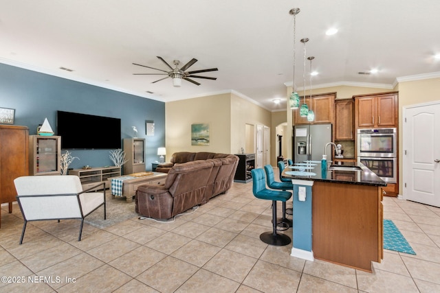 417 Palazzo Cir, Saint Augustine, FL 32092 - kitchen featuring appliances with stainless steel finishes, light tile patterned floors, ceiling fan, brown cabinetry, and ornamental molding