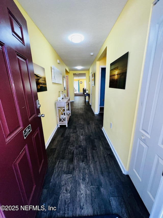 corridor featuring wood finished floors and baseboards