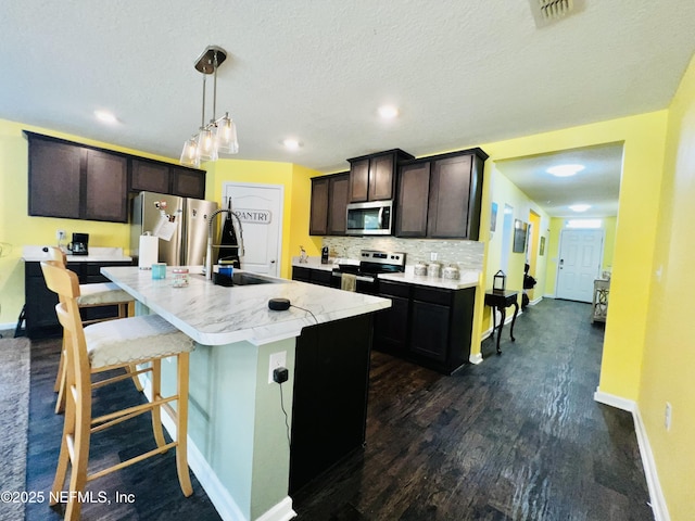kitchen with a sink, appliances with stainless steel finishes, visible vents, light countertops, and baseboards