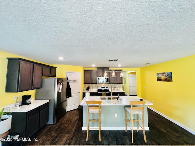 kitchen featuring stainless steel appliances, dark wood-type flooring, backsplash, light countertops, and dark brown cabinets