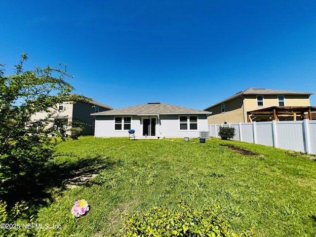 back of property featuring fence, cooling unit, and a yard