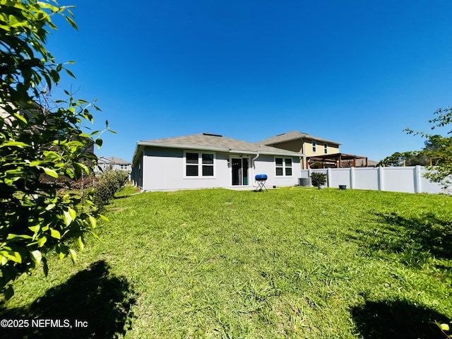 back of house with a lawn, central AC, stucco siding, and fence