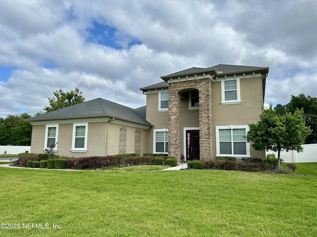 view of front facade featuring fence, stucco siding, and a front lawn