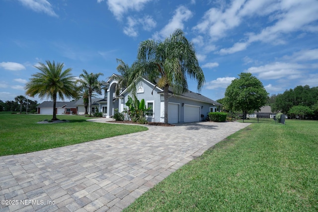 view of front of home featuring fence, decorative driveway, a front lawn, and a garage