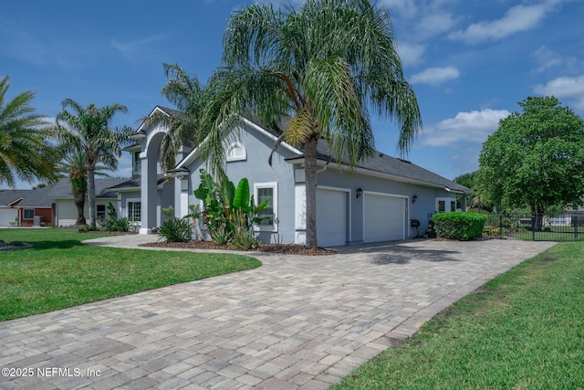 view of side of home featuring stucco siding, decorative driveway, a lawn, fence, and a garage