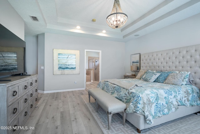bedroom featuring visible vents, a chandelier, a tray ceiling, baseboards, and light wood-type flooring
