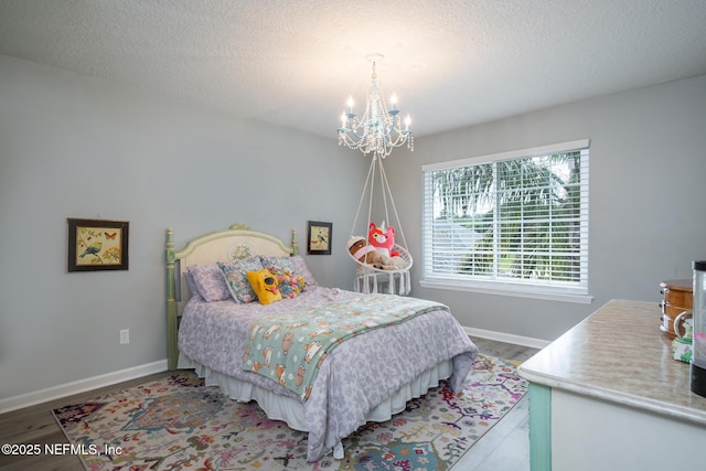 bedroom featuring baseboards, wood finished floors, a notable chandelier, and a textured ceiling