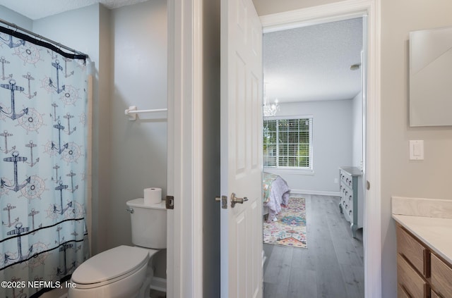bathroom with a shower with curtain, vanity, a chandelier, toilet, and wood finished floors