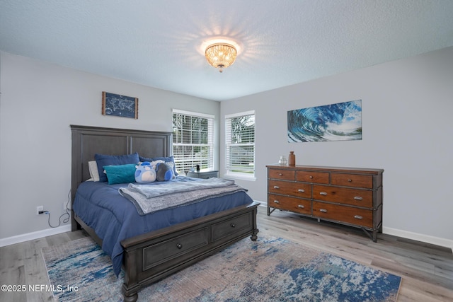 bedroom featuring a textured ceiling, wood finished floors, and baseboards