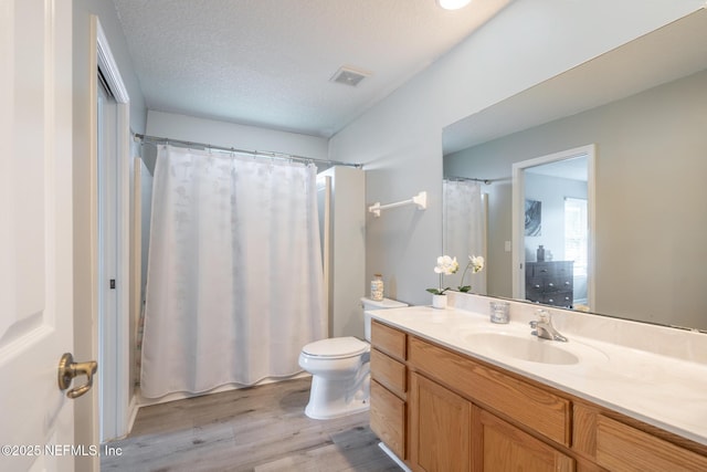 bathroom with a shower with curtain, visible vents, toilet, wood finished floors, and vanity