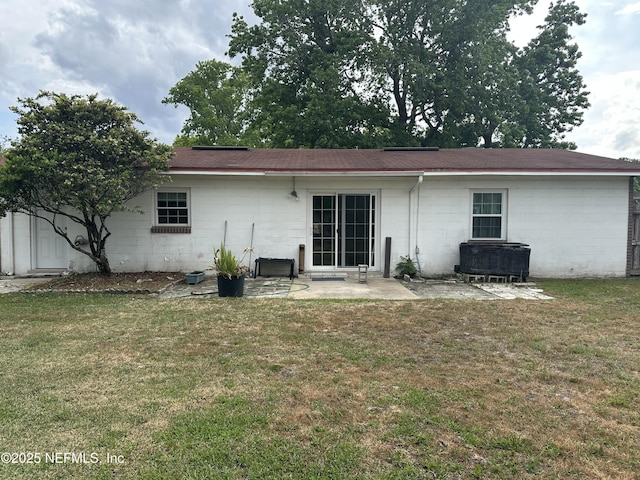 rear view of property with a yard, concrete block siding, and a patio area