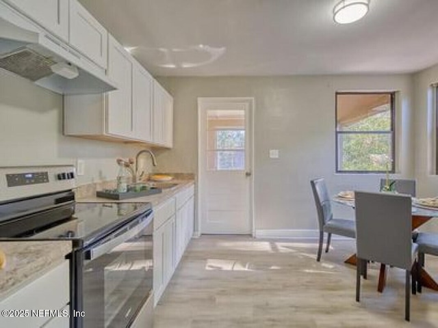 9717 Carbondale Dr W, Jacksonville, FL 32208 - kitchen featuring light wood finished floors, a sink, under cabinet range hood, stainless steel electric range oven, and white cabinetry