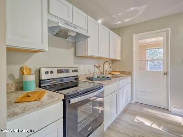 9717 Carbondale Dr W, Jacksonville, FL 32208 - kitchen featuring white cabinets, a sink, stainless steel electric stove, under cabinet range hood, and light wood-type flooring