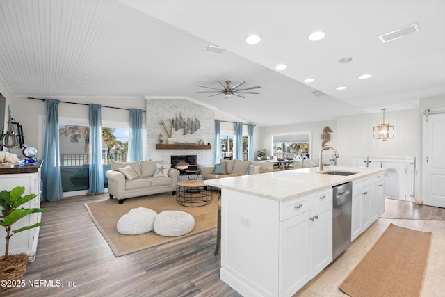 kitchen featuring a sink, a fireplace, white cabinetry, vaulted ceiling, and dishwasher